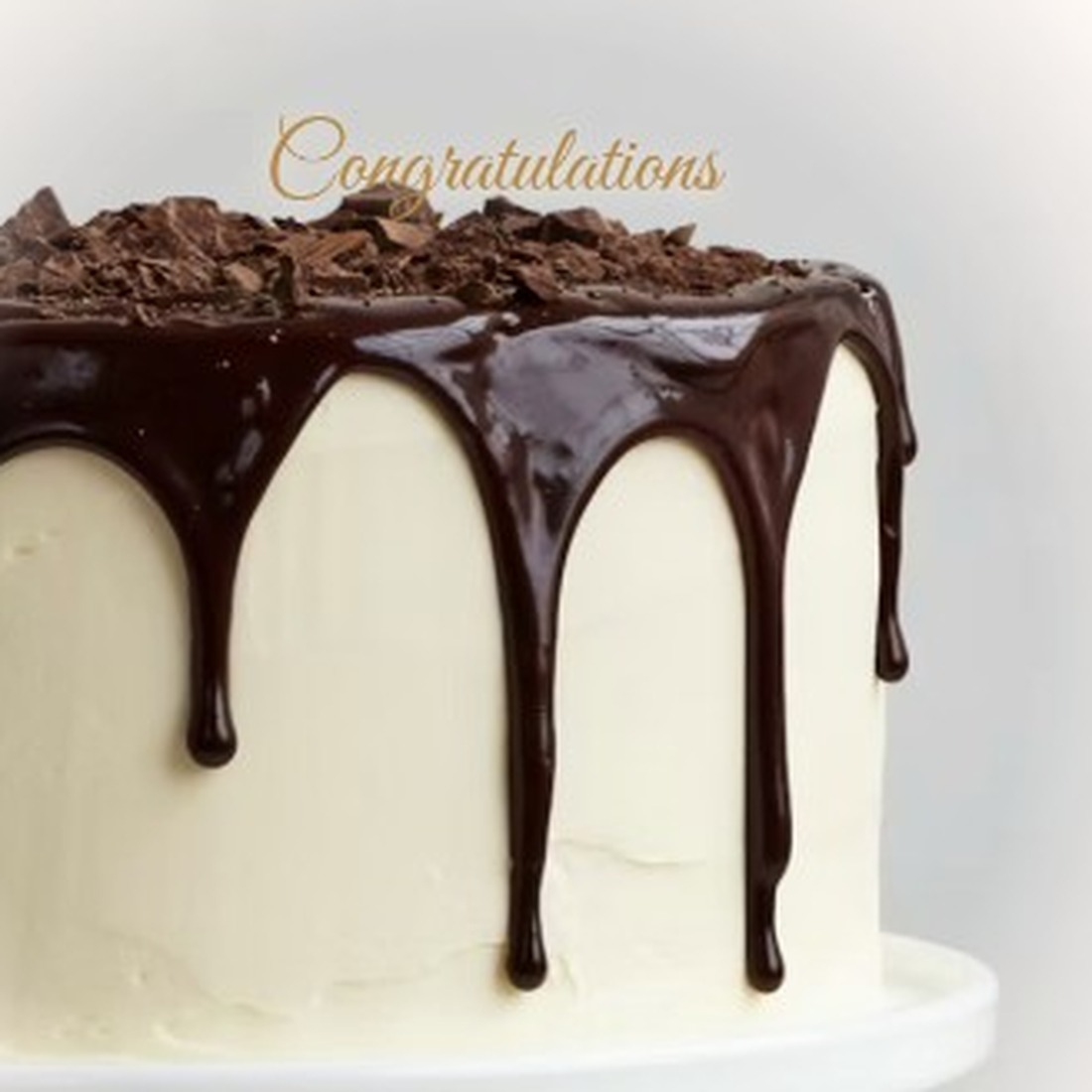 White frosted cake with chocolate drip, shavings and gold Congratulations topper